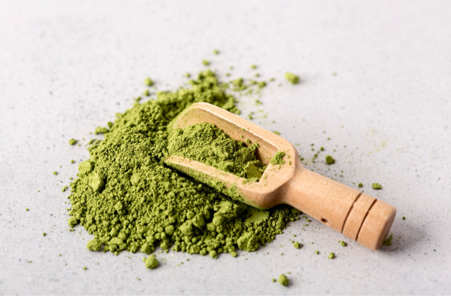 Green kratom powder in a bowl representing white vein kratom before final processing