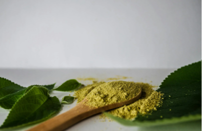 Green kratom powder on a wooden spoon