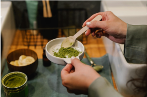Person holding a ceramic bowl of green powder representing white kratom morning routine