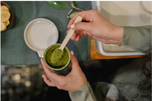 Person measuring green botanical powder illustrating kratom COA lab testing and quality verification 