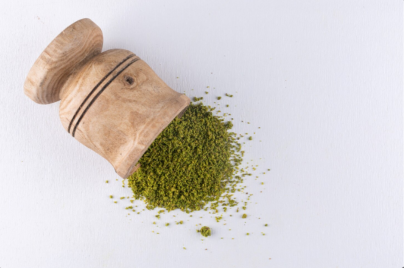 Green herbal powder in wooden mortar representing kratom for sale online Canada — Big Bear Kratom
